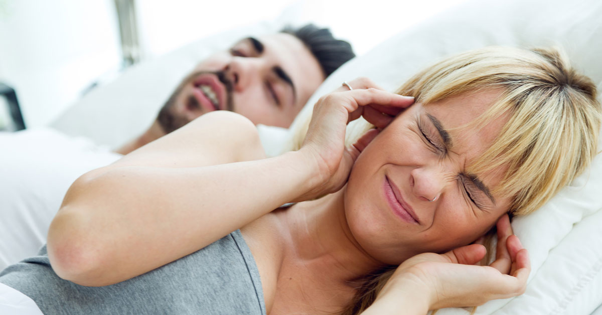 woman closing ears because of snoring