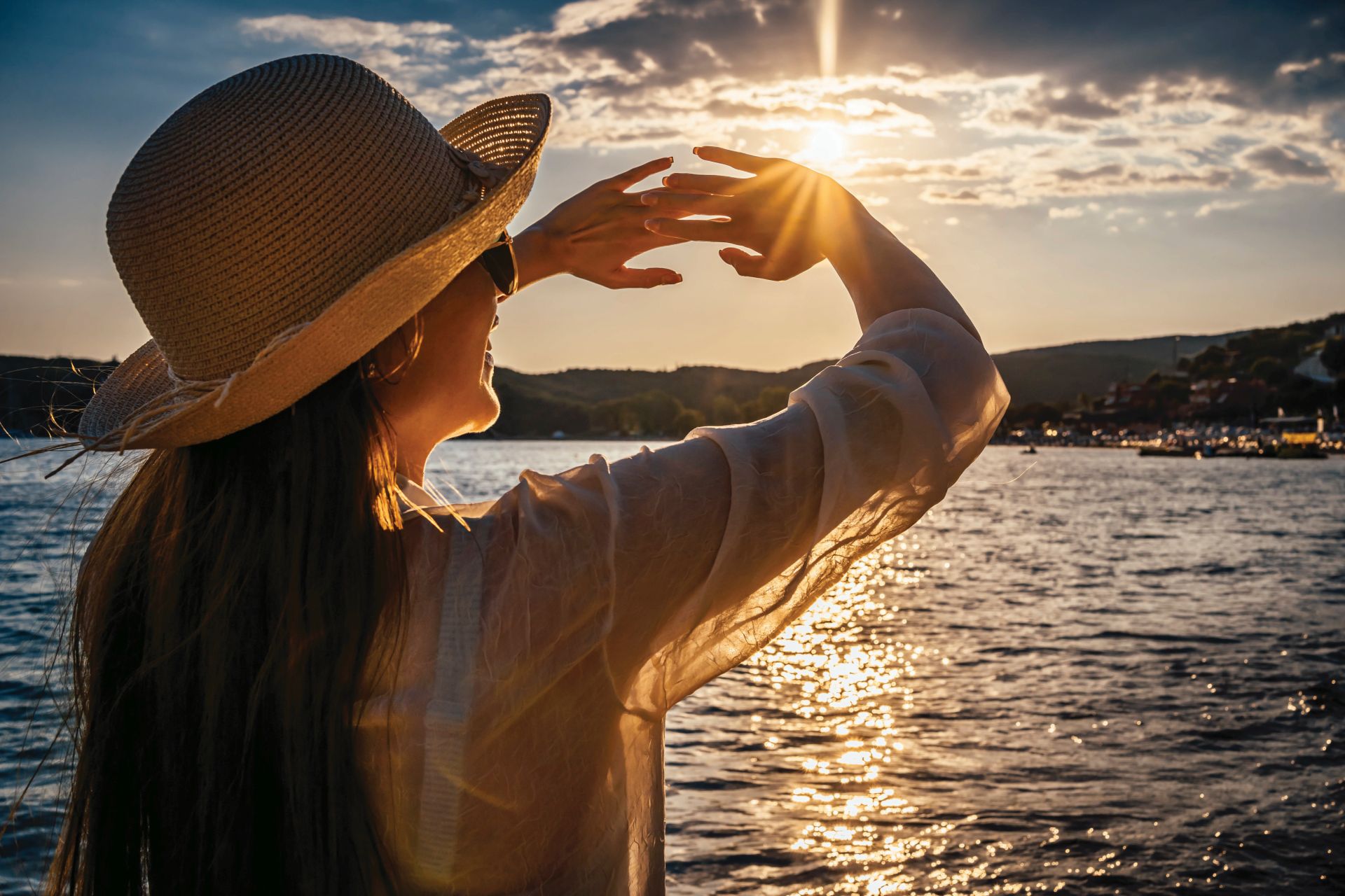 Young woman blocking sun with hands on the beach during sunset